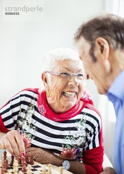 Glückliches älteres Paar  das sich beim Schachspielen im Pflegeheim ansieht.