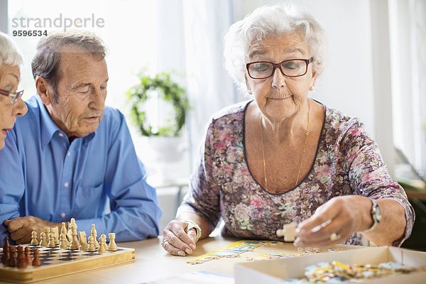 Senioren spielen Freizeitspiele am Tisch im Pflegeheim