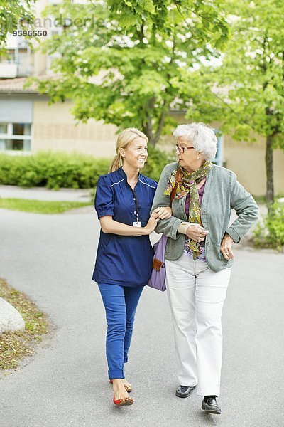 Volle Länge der lächelnden Frau  die mit der älteren Frau auf der Straße geht.