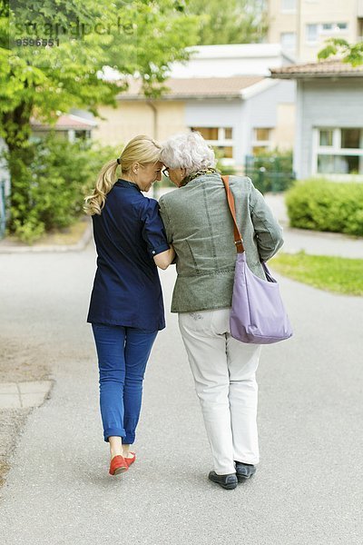 Durchgehende Rückansicht der zärtlichen Frau und Seniorin auf der Straße