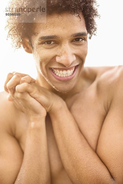 Porträt eines fröhlichen nassen Mannes ohne Hemd mit im Freien gefesselten Händen
