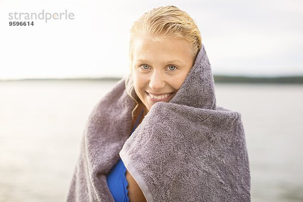 Porträt einer lächelnden Frau in Handtuch gewickelt gegen den See