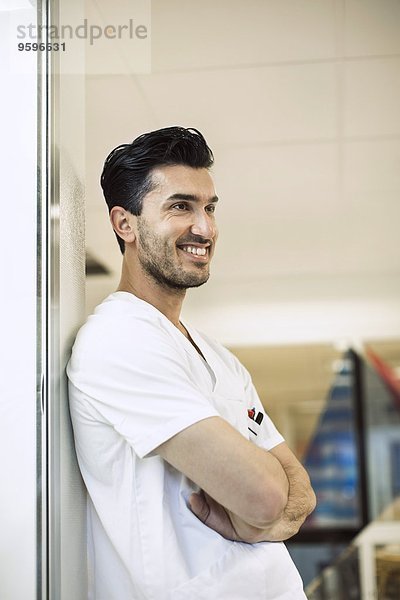 Lächelnder junger Arzt an der Wand im Krankenhaus