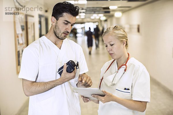 Ärzte und Ärztinnen diskutieren über digitale Tabletten im Krankenhausflur