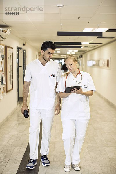 Volle Länge der Ärzte diskutieren über digitale Tabletten im Krankenhauskorridor