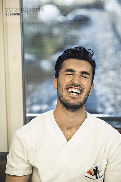 Junger männlicher Arzt lacht im Krankenhaus