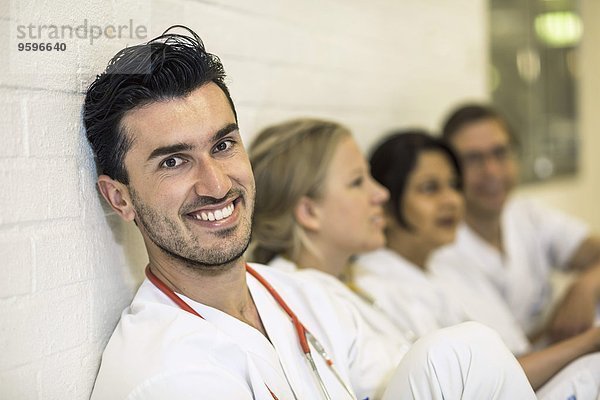 Porträt eines lächelnden Arztes mit Kolleginnen im Krankenhaus