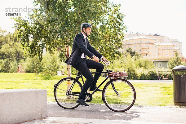 Volle Länge des Geschäftsmannes auf dem Fahrrad im Park