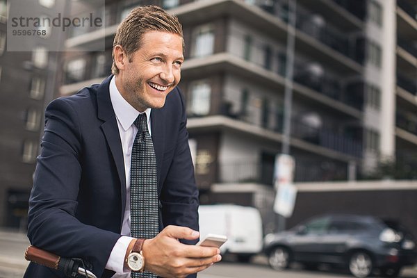 Glücklicher Geschäftsmann mit Smartphone in der Stadt