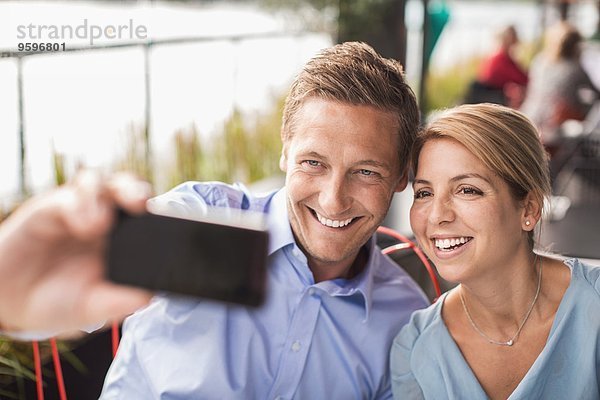 Lächelnde Geschäftsleute  die Selfie durch Smartphone im Cafe nehmen