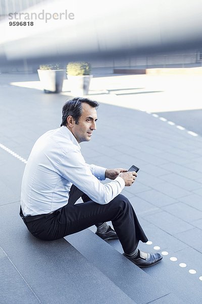 Seitenansicht des Geschäftsmannes bei der Benutzung des Mobiltelefons auf der Treppe