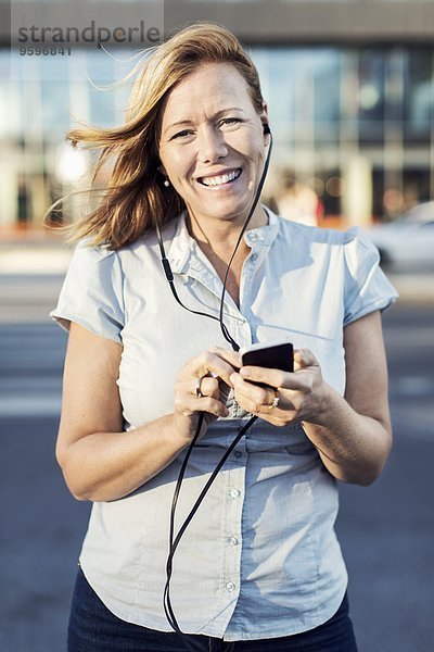 Porträt einer glücklichen Geschäftsfrau mit dem Handy im Freien