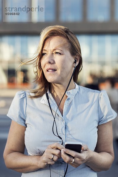 Geschäftsfrau schaut weg  während sie im Freien telefoniert