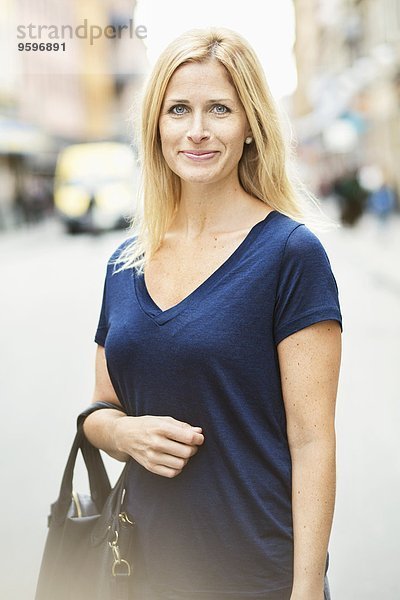 Portrait einer lächelnden erwachsenen Frau  die auf der Straße in der Stadt steht.