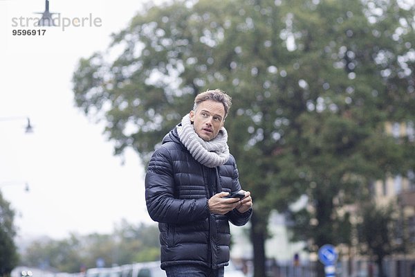 Erwachsener Mann mit Smartphone auf der Straße