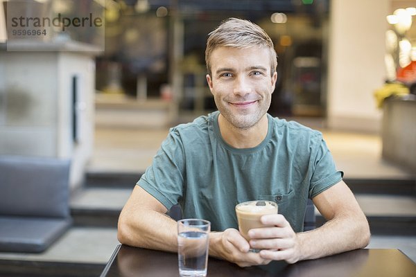 Porträt eines lächelnden jungen Mannes beim Kaffee im Restaurant