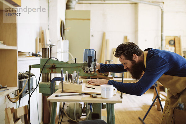Mittlerer erwachsener Handwerker mit Maschine in der Pfeifenorgel-Werkstatt