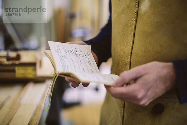 Nahaufnahme eines erwachsenen Handwerkers mit Notizbuch in der Orgelwerkstatt