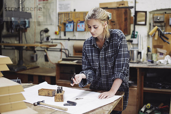 Junge Handwerkerin beim Prüfen von Bauteilen auf der Werkbank in der Pfeifenorgel-Werkstatt