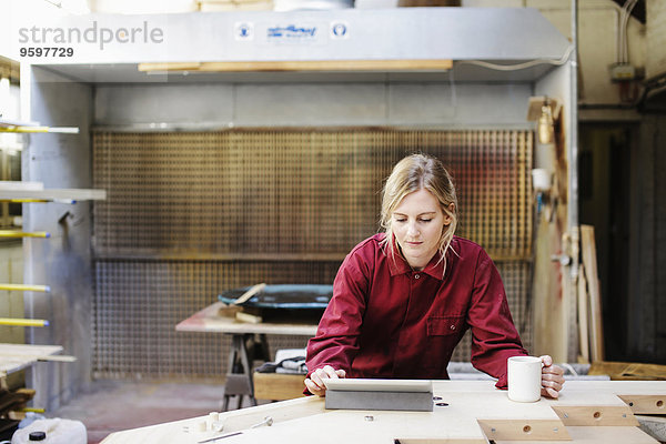 Junge Handwerkerin mit digitalem Tablett in der Pfeifenorgel-Werkstatt