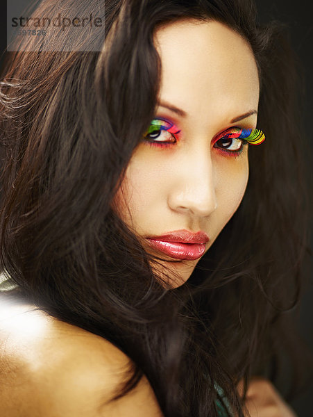 Junge Frau mit regenbogenfarbigen falschen Wimpern