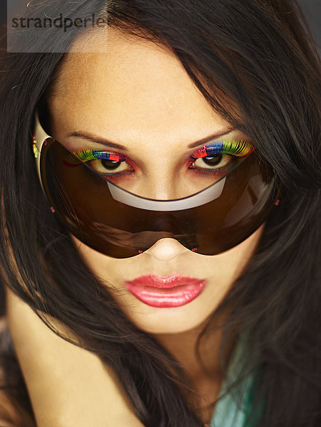 Junge Frau schaut über Sonnenbrille mit gefälschten Wimpern