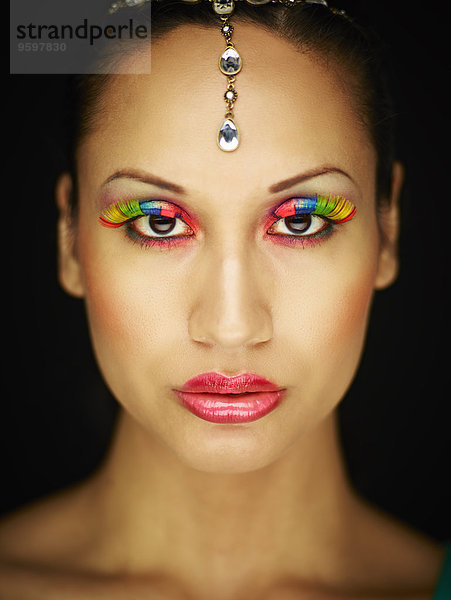 Junge Frau mit Schmuckkopf-Accessoire und farbigen Wimpern
