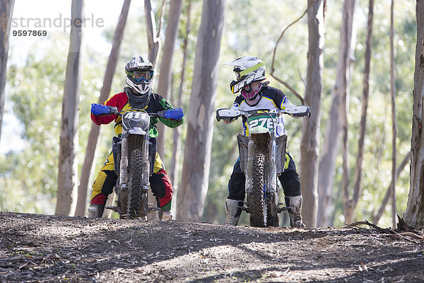 Zwei junge männliche Motocross-Fahrer im Wald im Gespräch