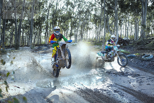 Zwei junge männliche Motocross-Fahrer auf staubiger Strecke