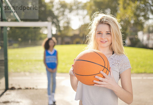Porträt einer jungen Frau  die Basketball hochhält.