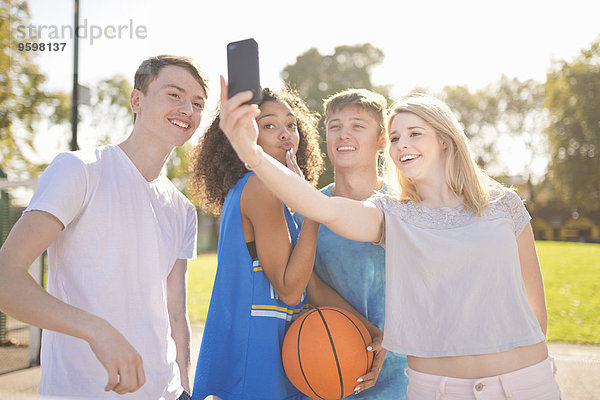Vier junge erwachsene Basketballspieler nehmen Smartphone Selfie