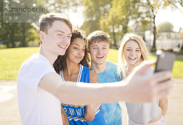 Vier junge erwachsene Basketballspieler posieren für Smartphone Selfie