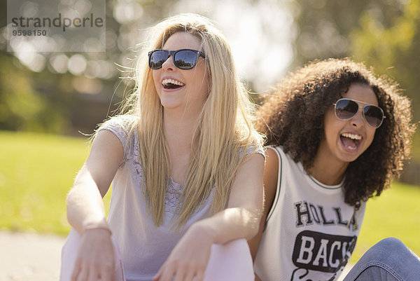 Zwei junge Freundinnen lachend im Park