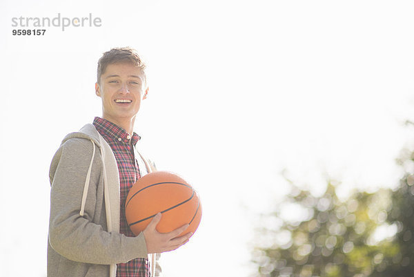 Porträt eines lächelnden jungen Mannes mit Basketball