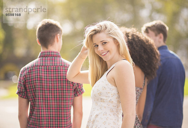 Junge Frau mit Freunden im Park mit Blick über die Schulter