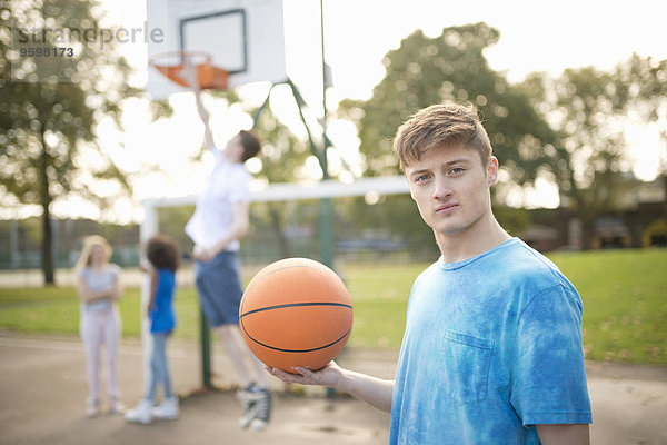 Porträt eines jungen Basketballspielers  der Basketball hält