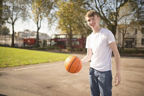 Porträt eines lächelnden Basketballspielers  der Basketball hält.