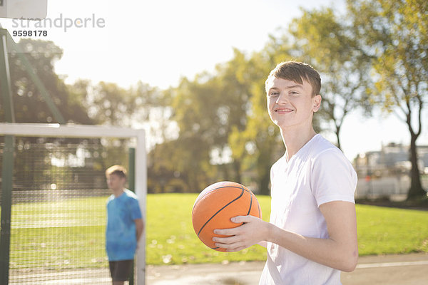 Porträt eines lächelnden jungen Basketballspielers auf dem Basketballplatz