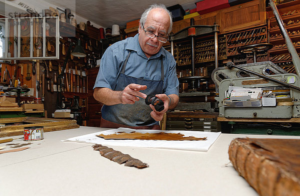 Senior Mann repariert zerbrechlichen Buchrücken in traditioneller Buchbinderei
