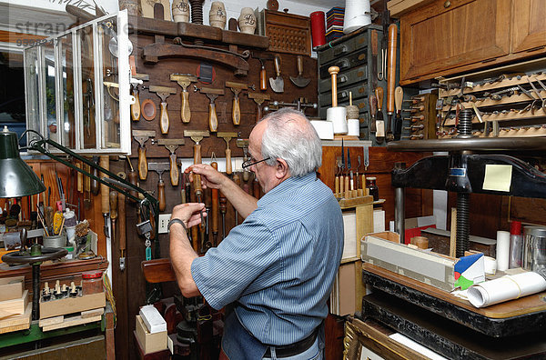 Senior Mann bei der Auswahl der Werkzeuge in der traditionellen Buchbinderei