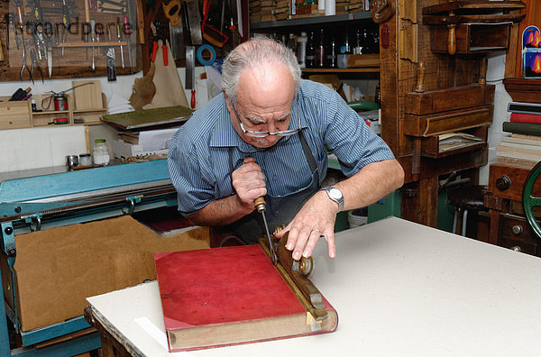 Senior Mann beim Restaurieren von Büchern in der traditionellen Buchbinderei