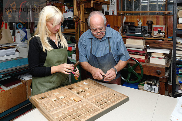 Senior Mann und junge Frau beim Zusammenbau von Buchdruck in der traditionellen Buchbinderei