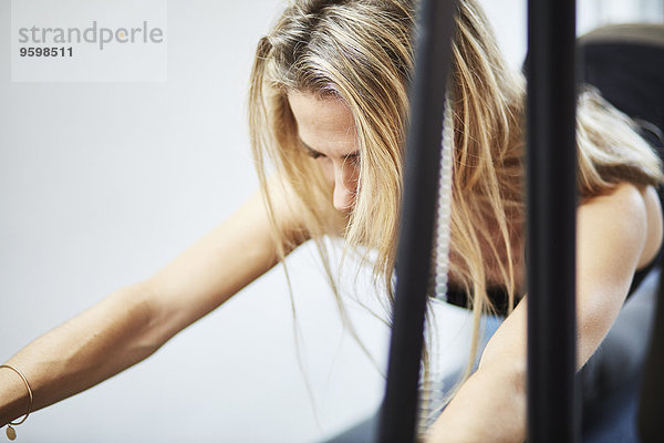 Nahaufnahme der reifen Frau  die Pilates auf dem Trapeztisch in der Pilates Turnhalle übt.