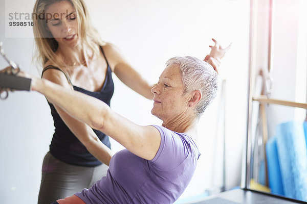 Schülerin und Lehrerin übt Pilates auf dem Trapeztisch in der Pilates Turnhalle.