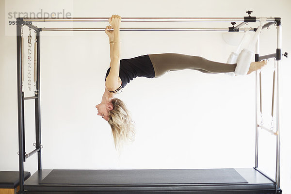 Reife Frau übt Pilates auf dem Trapeztisch in der Pilates Turnhalle.