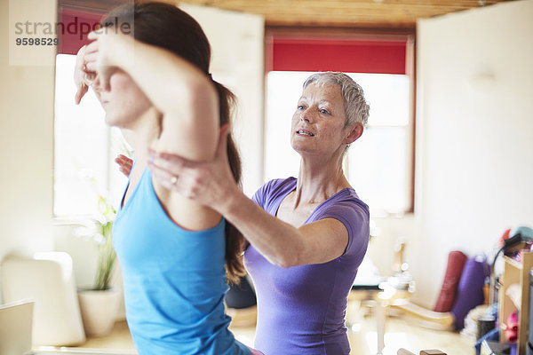 Junge Studentin und Tutorin im Pilates Fitnessstudio