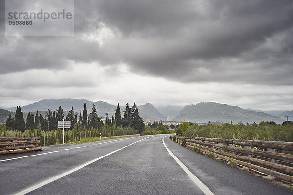 Leere Straße durch ländliche Landschaft  graue Wolken oben  Mallorca  Spanien