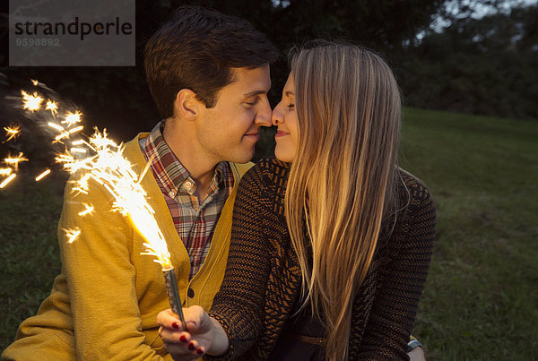 Junges Paar Nase an Nase im Park mit funkelndem Feuerwerk