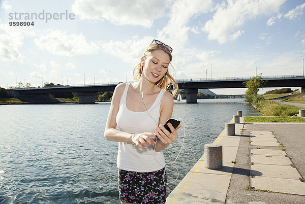 Junge Frau beim SMSen auf Smartphone auf der Donauinsel  Wien  Österreich