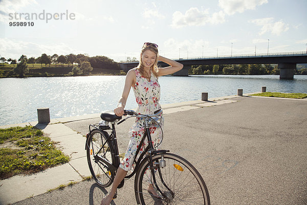 Portrait einer jungen Frau mit Fahrrad am Flussufer  Donauinsel  Wien  Österreich